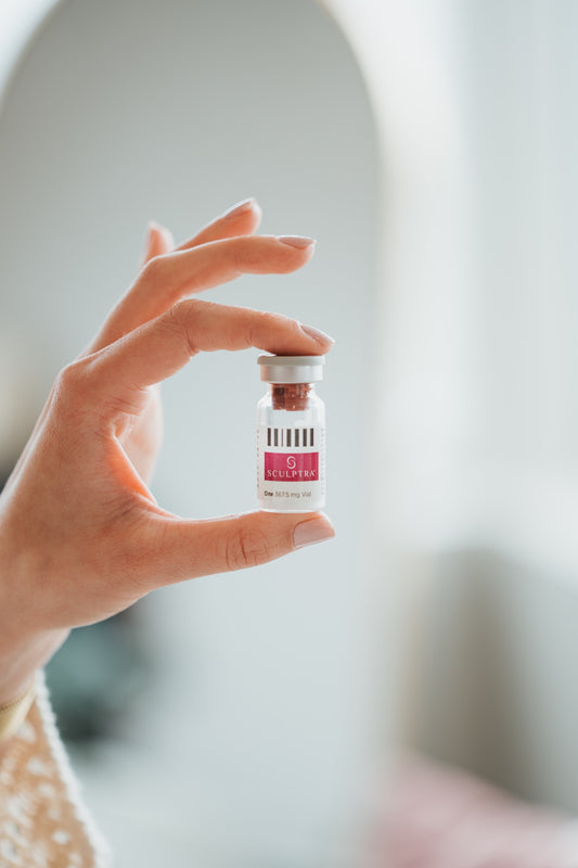 Hand holding a vial of Sculptra in a bright treatment space at Bloom Aesthetics in Spokane