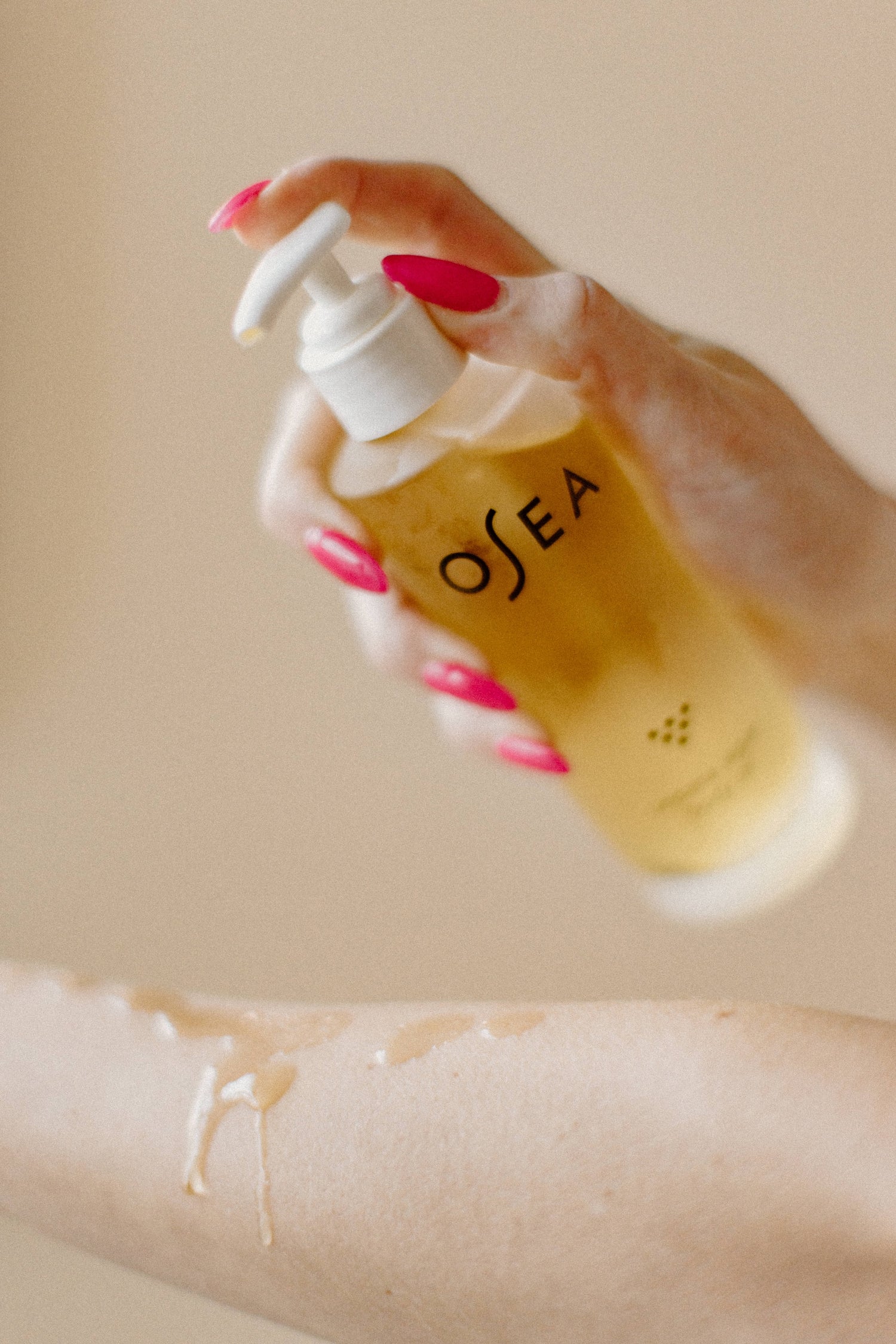 Hand holding a bottle of OSEA product to enhance sugaring and waxing treatment at Bloom Aesthetics