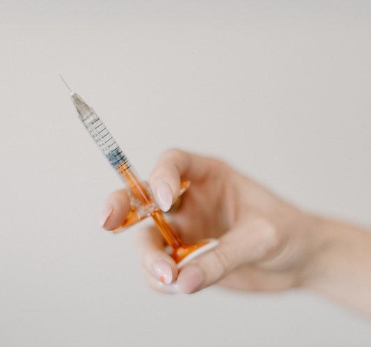 Hand holding a syringe of dermal/lip filler at Bloom Aesthetics